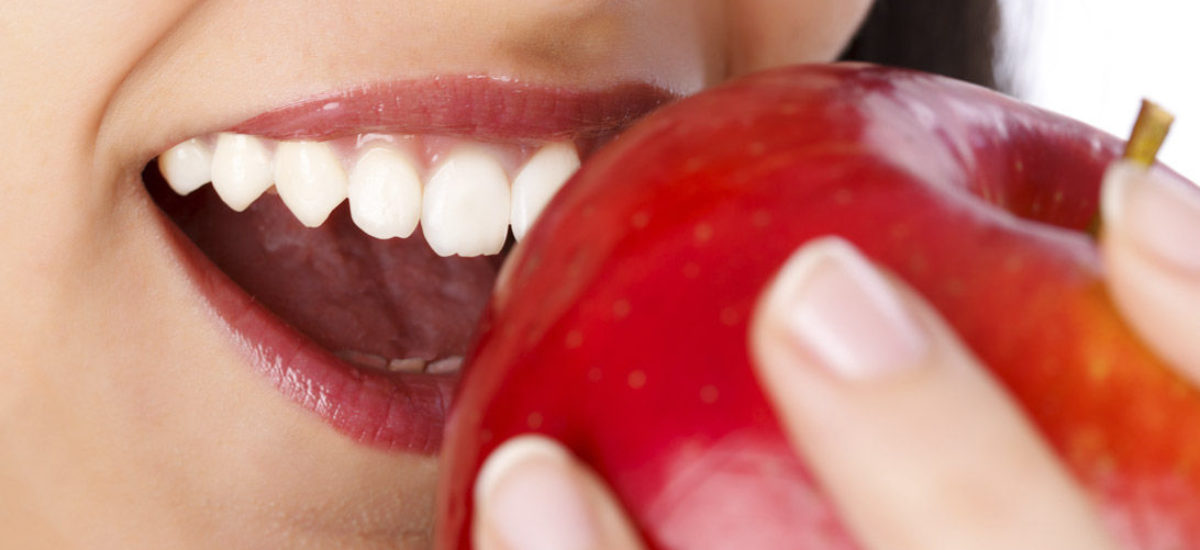 Sonrisa saludable mordiendo una manzana — filosofía de la Clínica Dental Mendizábal de Logroño
